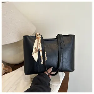 Nahaufnahme der schwarzen Retro-Leder-Einkaufstasche mit geometrischem Seidenschal