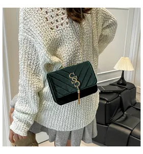 Gros plan détaillé du sac en velours vert foncé avec franges dorées et texture matelassée