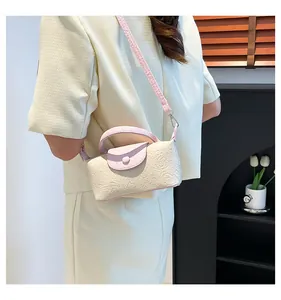 Detail of cream crossbody bag featuring floral embossing and soft pink leather trim