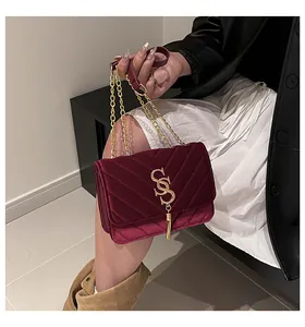 Détail du sac en velours bordeaux avec matelassage en V et chaîne à pompon doré