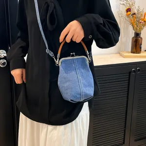 Vintage wash blue denim shell bag with leather handles and white stitching for women