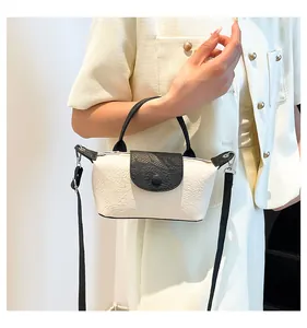 Detail of small crossbody bag with white dragon pattern embossing and black handles