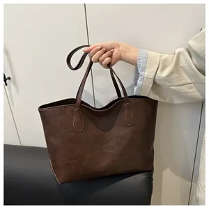 Close-up of a large dark brown tote bag in vintage synthetic leather with reinforced straps
