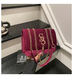 Détail du sac à main en velours bordeaux avec texture matelassée en V et pompon doré