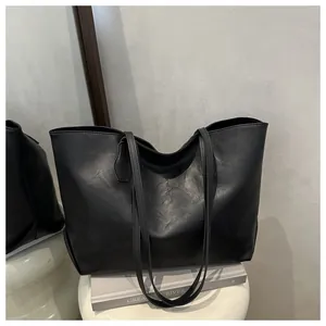 Close-up of black matte faux leather tote bag with fine grain texture and shoulder straps