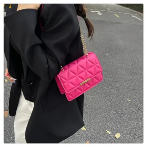 Street style view of a rose pink quilted crossbody bag with a gold chain strap