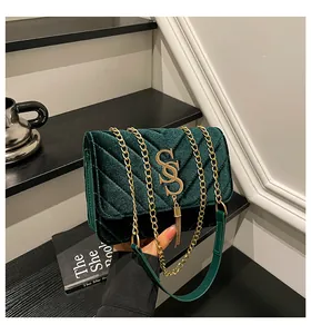 Détail du sac en velours vert foncé avec texture matelassée en V, logo SS et frange