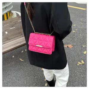 Detail of fuchsia quilted crossbody bag with gold chain strap on a fashion model