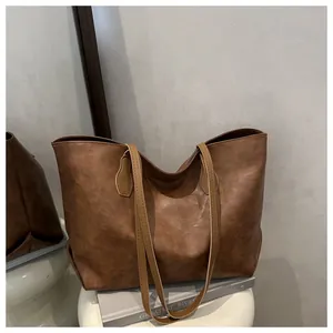 Detail of dark brown tote bag with premium leather texture on a minimalist white stool