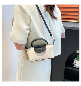 Detail of the mini crossbody bag featuring cream embossed texture and black snake print flap