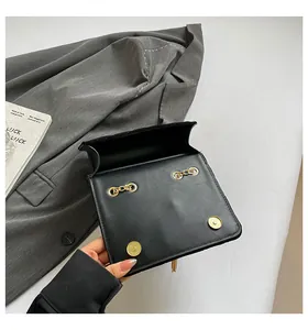 Détail du sac en cuir noir montrant le double fermoir magnétique doré et les anneaux
