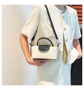 Detailed side view of a stylish textured leather handbag worn by a model in a beige jacket