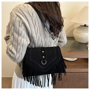 Detail einer schwarzen Wildledertasche mit Fransen und Goldnieten an einem Model