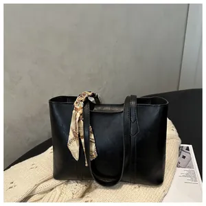 Detail der schwarzen Shopper-Tasche aus Kunstleder mit Seidenschal und breiten Schultergurten