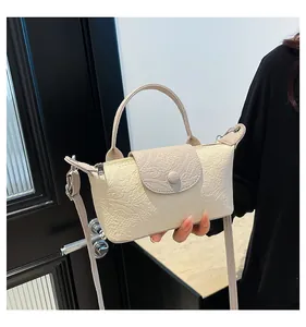 Detail of beige faux crocodile leather texture and semi-circular buckle on crossbody bag