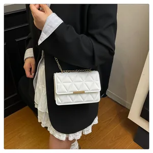 Detail of white quilted crossbody bag with gold hardware buckle and elegant metal chain