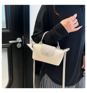 Detail of cream and gray crossbody bag featuring textured embossed floral pattern