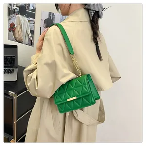 Green quilted small square bag with gold chain strap shown on a model in a modern office