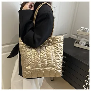 Close-up of golden quilted puffer tote bag featuring metallic finish and wide handles
