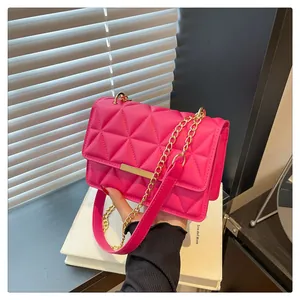 Detailed shot of hot pink quilted crossbody bag with gold metal trim and chain strap