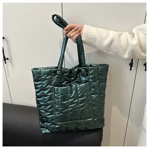 Close-up of green quilted down tote bag with glossy metallic finish and front pocket