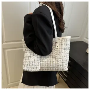 Détail du sac cabas en tweed beige avec anses en cuir et petite pochette assortie