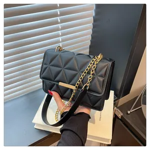 Detail of black quilted leather shoulder bag featuring gold chain and rectangular metal clasp