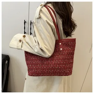 Gros plan sur la texture en tweed bordeaux et les rivets d'un sac cabas élégant