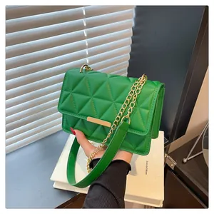 Detail of green quilted handbag with golden chain strap and textured flap pattern