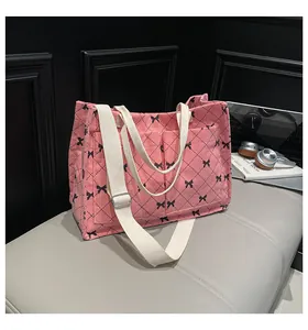 Detail of pink corduroy tote bag featuring quilted pattern and black bow accents