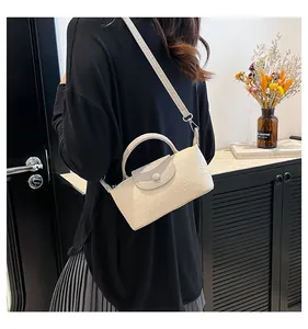 Detail of cream mini handbag featuring embossed floral patterns and elegant top handle