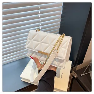 Close-up of white quilted crossbody bag with gold chain strap and elegant metal bar detail