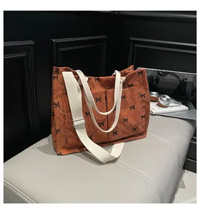 Detail of orange corduroy tote bag featuring black bow patterns and quilted textures