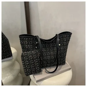 Détail d'un cabas en tweed tissé noir et or avec des rivets métalliques élégants