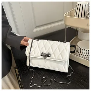 Detailed view of white quilted crossbody bag with metal chain strap and triangle buckle