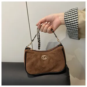 Close-up of brown suede bag with quilted diamond stitching and gold chain strap detail