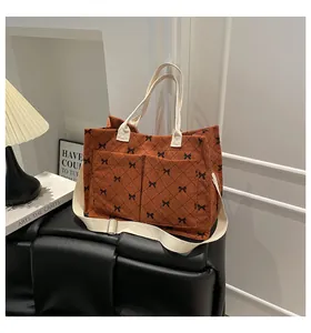 Detail of brown corduroy tote bag with black bow lattice pattern and front pockets
