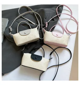 Detailed macro view of three textured leather mini handbags in grey, pink, and black