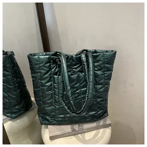 Close-up of a dark green glossy quilted tote bag with padded texture and wide straps