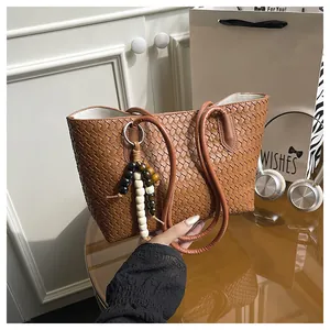 Detail of woven brown tote bag featuring decorative wooden beads and premium texture