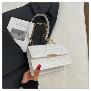 Close-up of white quilted square bag with triangular texture and gold metal chain strap