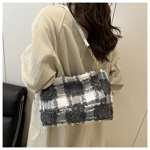 Detail of tweed checkered bag showing fringe edges and gold chain leather strap