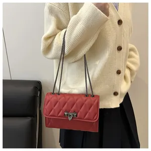 Detail of red quilted faux leather shoulder bag with triangle metal chain lock