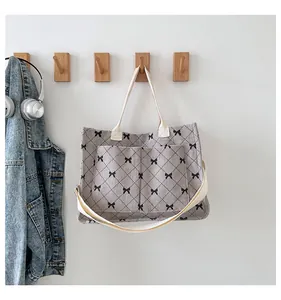 Detail of grey corduroy tote bag with bow and diamond pattern on wooden wall hook