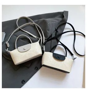 Detail of embossed texture and flap closure on minimalist small square handbag