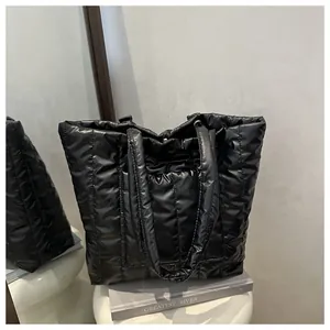 Detail of black quilted puffer tote bag with glossy finish and vertical stripe stitching