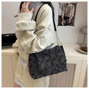 Detail of grey checkered shoulder bag with fringe texture and gold chain strap