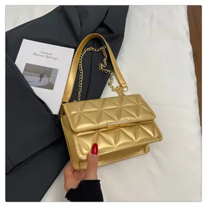 Detail of gold quilted handbag showing triangular stitching and metal chain strap