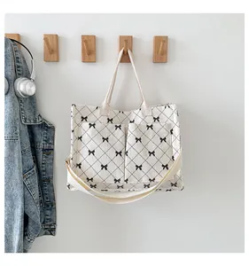 Detail of cream corduroy tote with black quilted patterns and tiny bow accents