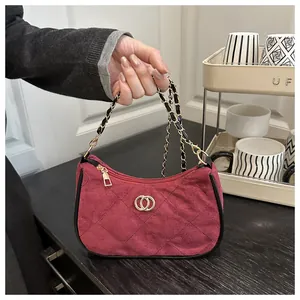 Macro detail of wine red suede quilted bag featuring gold double-ring buckle and chain strap